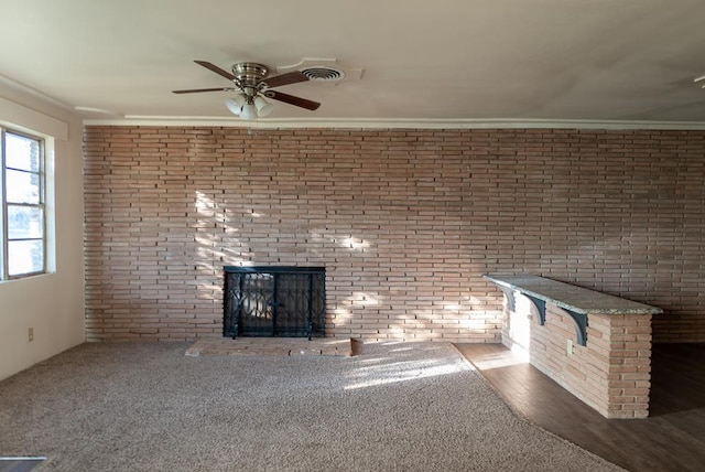 unfurnished living room with dark carpet, a brick fireplace, ceiling fan, and ornamental molding