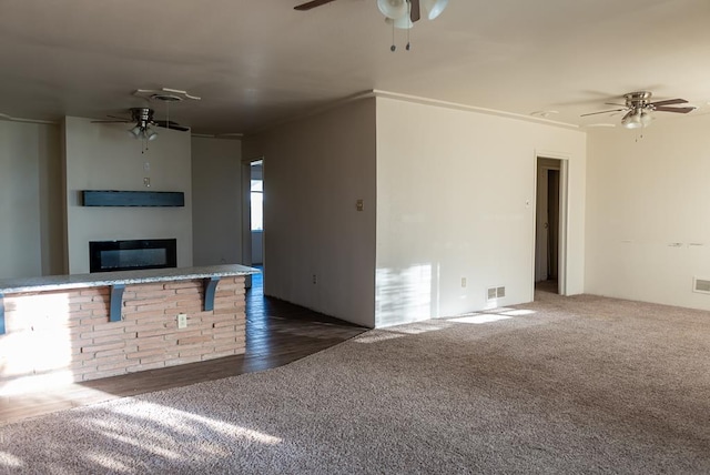 unfurnished living room featuring ceiling fan and dark colored carpet