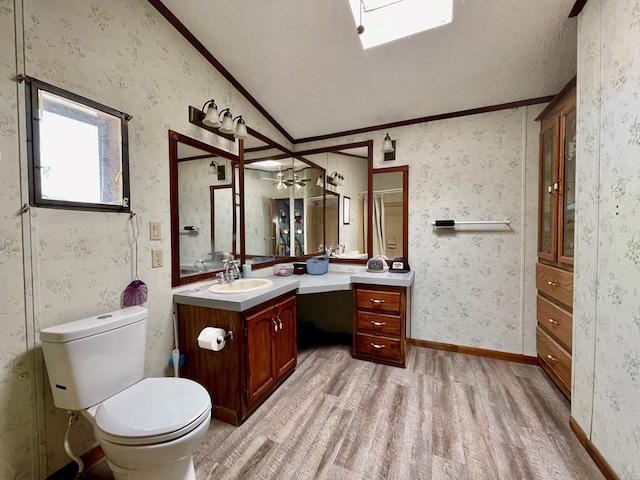 bathroom featuring a textured ceiling, lofted ceiling, hardwood / wood-style flooring, vanity, and ornamental molding