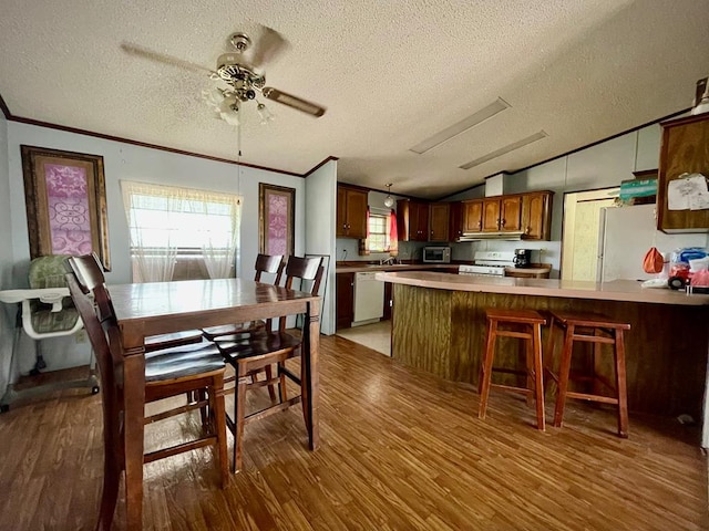 dining area with hardwood / wood-style floors, a textured ceiling, ornamental molding, and lofted ceiling