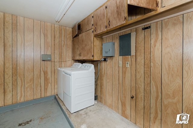 laundry area featuring electric panel, independent washer and dryer, and wooden walls