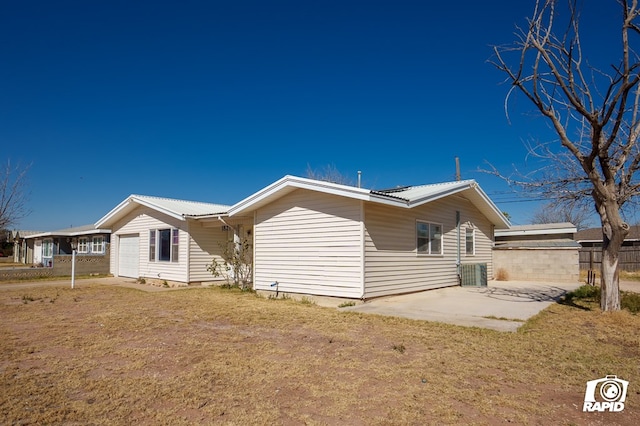 rear view of property featuring metal roof, a lawn, and a patio