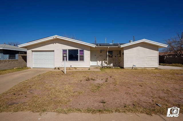 single story home featuring solar panels, a porch, fence, a garage, and driveway