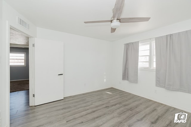 unfurnished room featuring a ceiling fan, baseboards, visible vents, and wood finished floors