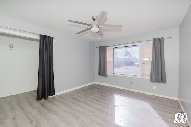 spare room featuring a ceiling fan, baseboards, and wood finished floors