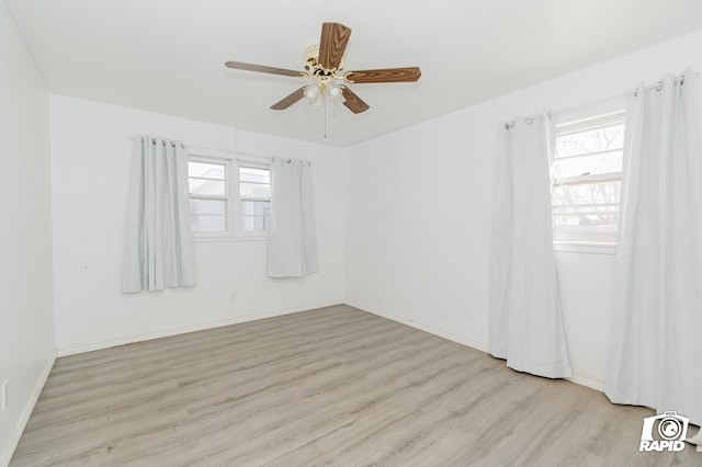 spare room with light wood finished floors, ceiling fan, and baseboards