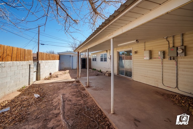 view of patio / terrace featuring a storage shed, fence, and an outbuilding