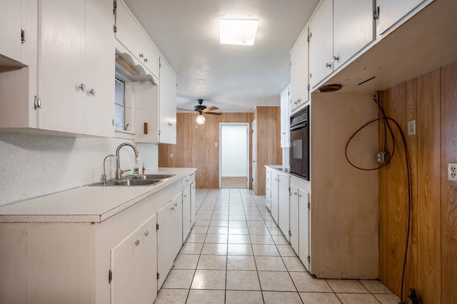 kitchen with sink, wood walls, and white cabinetry