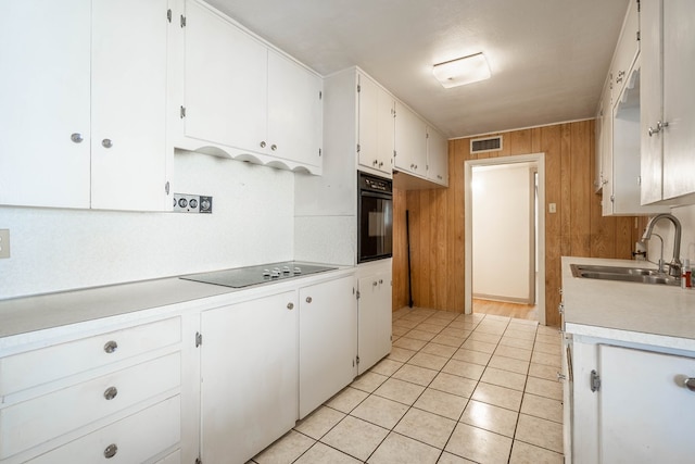 kitchen with light tile patterned floors, white cabinetry, sink, and black appliances