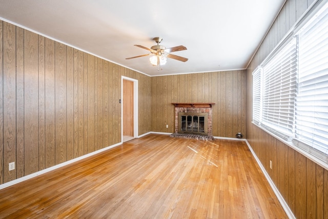 unfurnished living room featuring a fireplace, light hardwood / wood-style flooring, and wooden walls