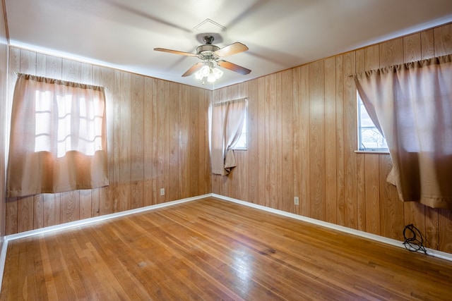 unfurnished room featuring ceiling fan, hardwood / wood-style floors, and wooden walls