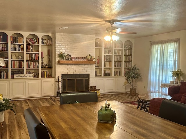 dining area with dark wood-type flooring, a textured ceiling, and a brick fireplace