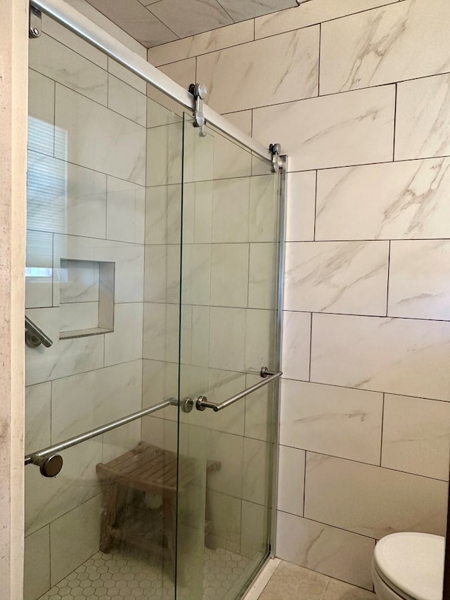 bathroom featuring tile patterned flooring, toilet, and a shower with shower door