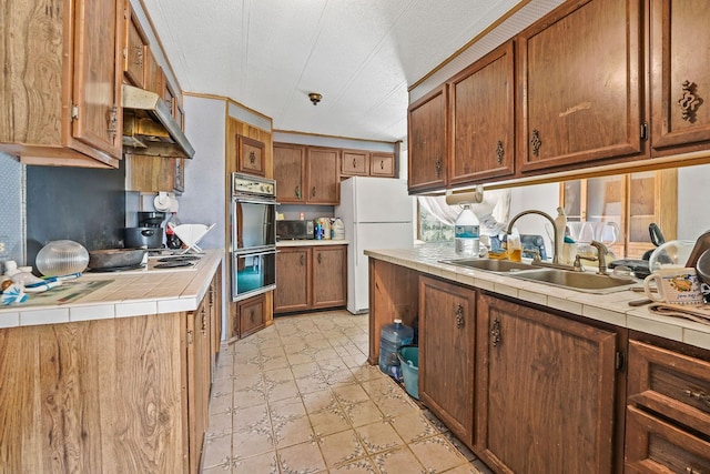 kitchen with tile countertops, white refrigerator, sink, and double oven