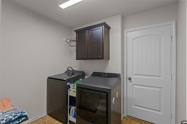 clothes washing area with cabinets, light tile patterned floors, and washing machine and clothes dryer