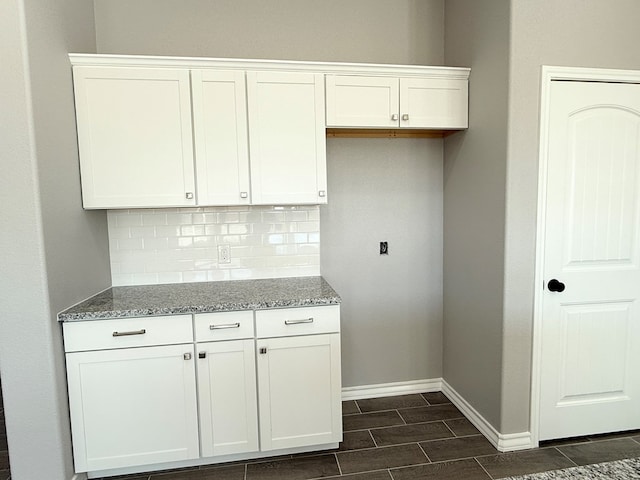 kitchen with decorative backsplash, white cabinetry, dark wood-type flooring, and light stone counters