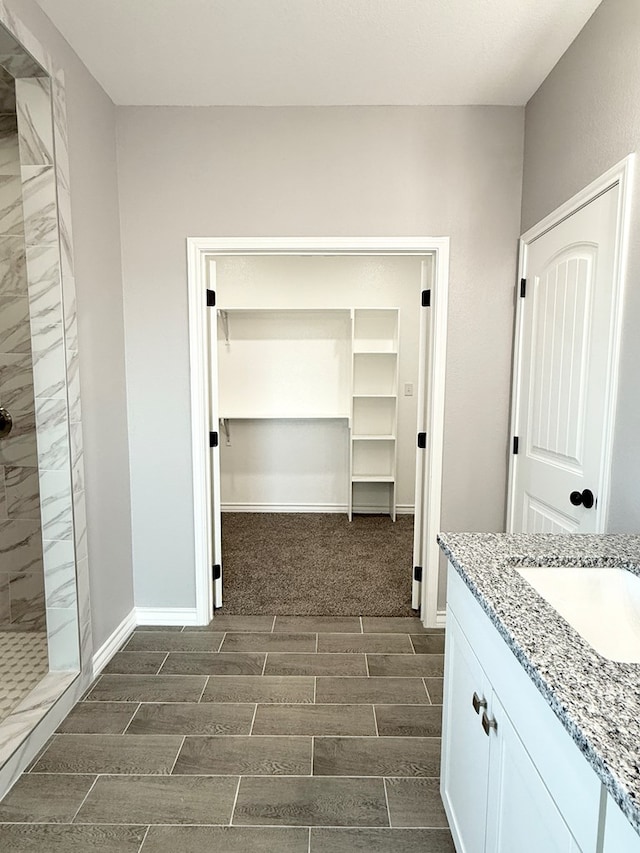 bathroom featuring a tile shower and vanity