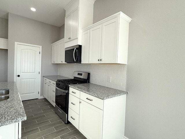 kitchen with backsplash, white cabinets, dark hardwood / wood-style floors, light stone countertops, and appliances with stainless steel finishes