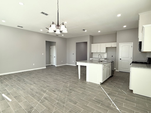 kitchen featuring a kitchen island with sink, sink, decorative light fixtures, an inviting chandelier, and white cabinetry