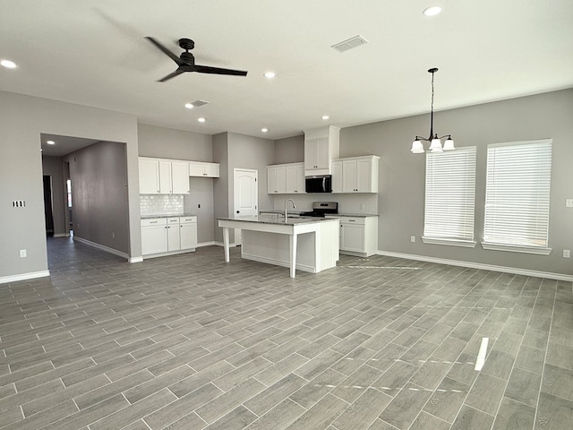 kitchen featuring appliances with stainless steel finishes, white cabinetry, an island with sink, and light wood-type flooring