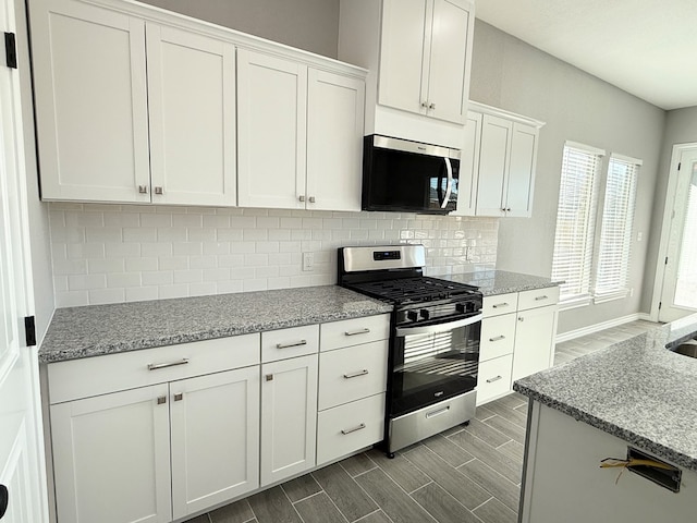 kitchen with light stone countertops, appliances with stainless steel finishes, backsplash, hardwood / wood-style floors, and white cabinetry