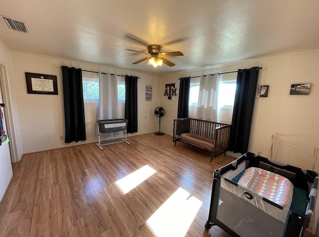 unfurnished bedroom with multiple windows, ceiling fan, wood-type flooring, and a textured ceiling