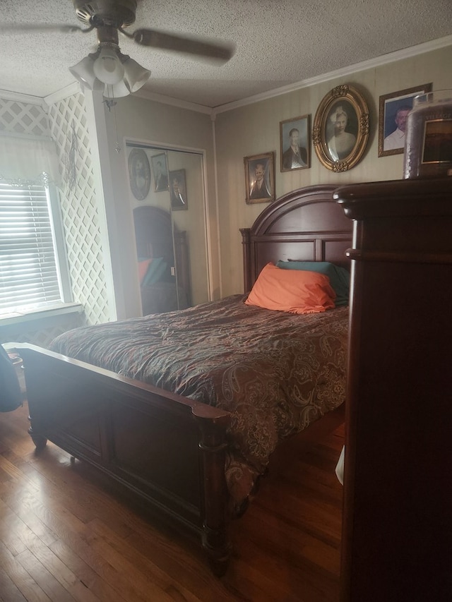 bedroom with dark wood-type flooring, ceiling fan, ornamental molding, a textured ceiling, and a closet