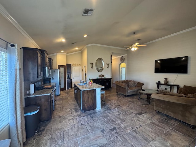 kitchen with a kitchen bar, appliances with stainless steel finishes, an island with sink, and dark brown cabinetry