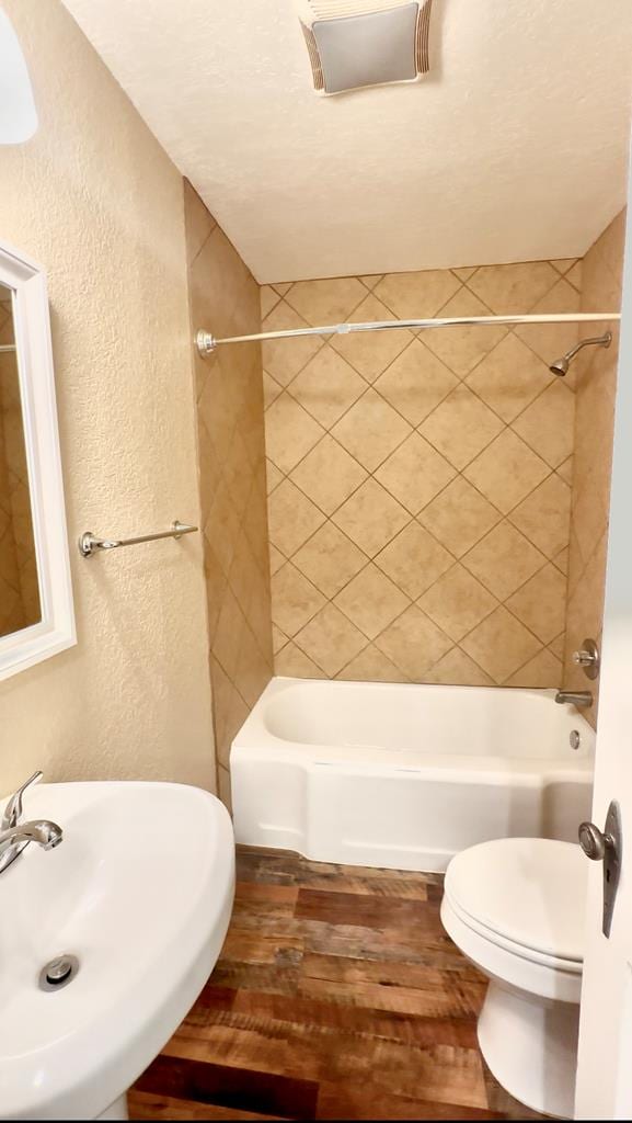 full bathroom featuring sink, tiled shower / bath, wood-type flooring, and toilet