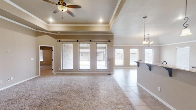 unfurnished living room featuring a tray ceiling, light carpet, light tile patterned floors, and ornamental molding