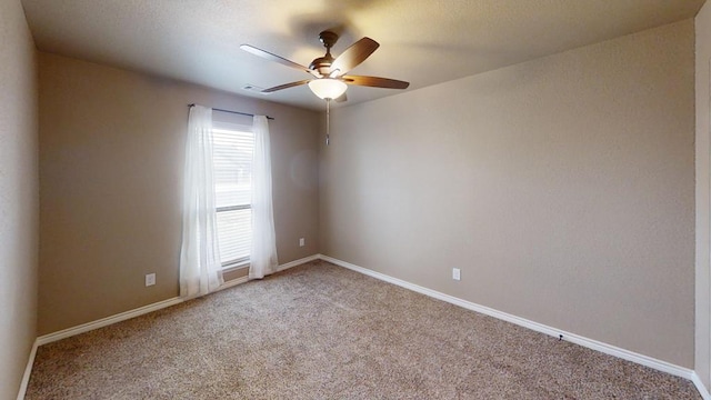 carpeted spare room with visible vents, a ceiling fan, and baseboards