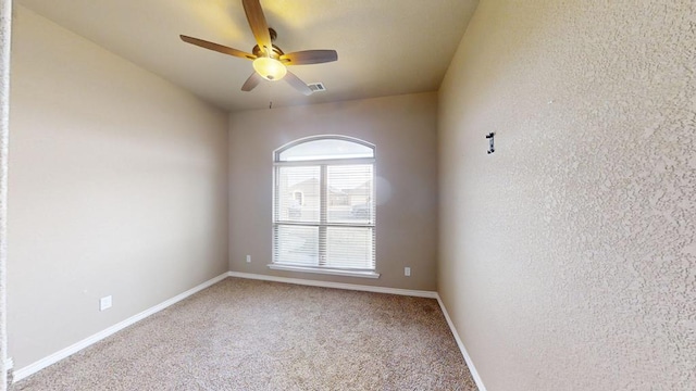 empty room featuring a ceiling fan, baseboards, visible vents, a textured wall, and light colored carpet