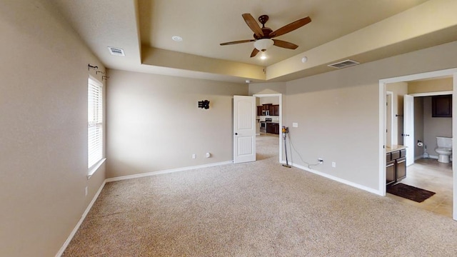 spare room featuring a raised ceiling, baseboards, and visible vents