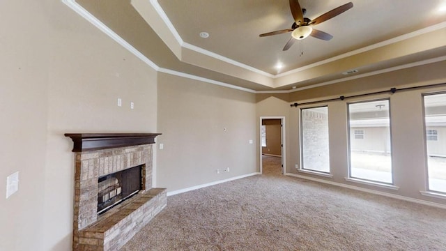 unfurnished living room with a brick fireplace, baseboards, a tray ceiling, and ornamental molding