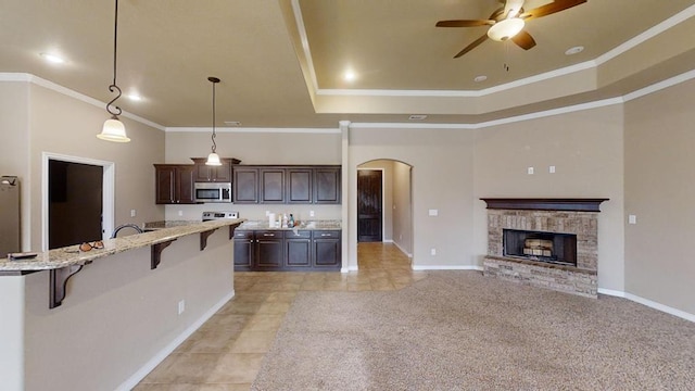 kitchen featuring arched walkways, ceiling fan, dark brown cabinets, a kitchen bar, and stainless steel microwave