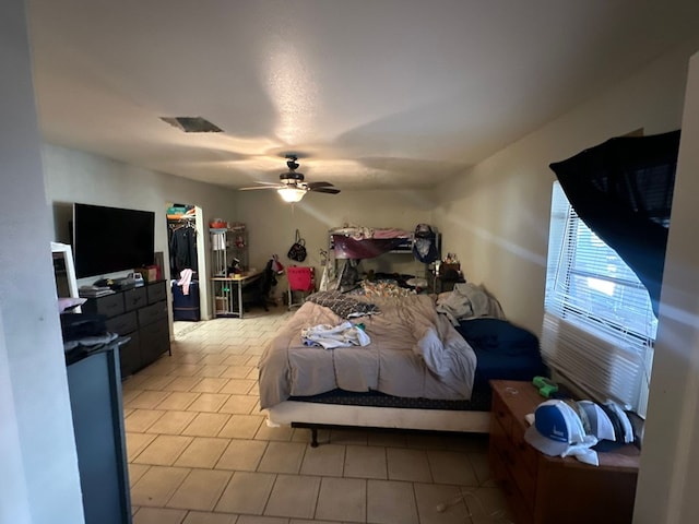 tiled bedroom with ceiling fan, a spacious closet, and a closet