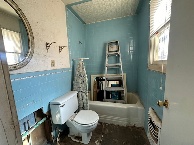 bathroom featuring tile walls, shower / bathing tub combination, and toilet