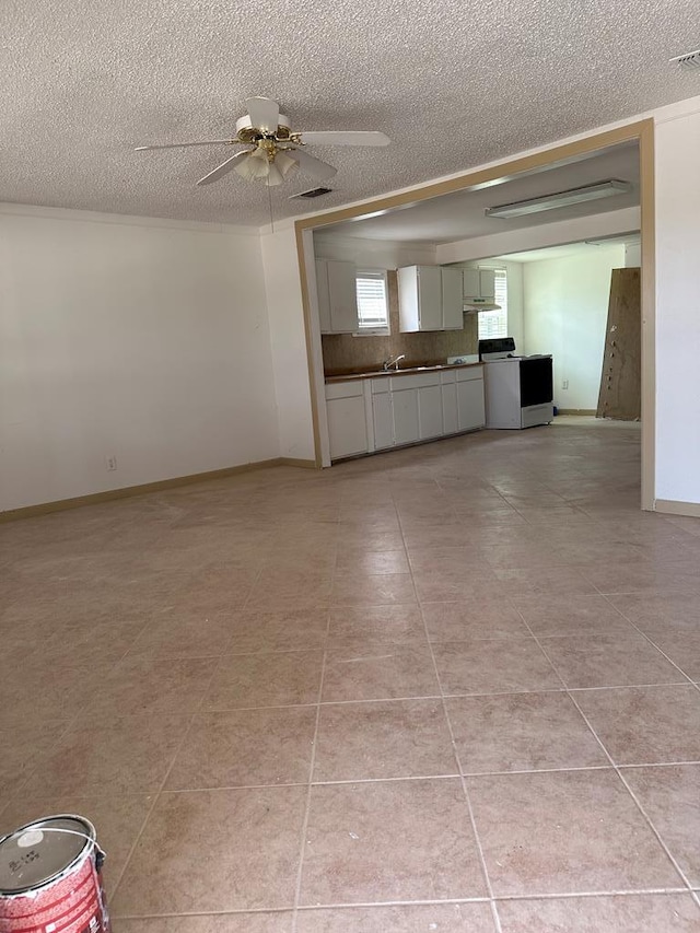 interior space featuring ceiling fan, sink, light tile patterned floors, and a textured ceiling