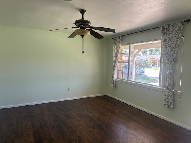 empty room with dark wood-style floors, a textured ceiling, a ceiling fan, and baseboards