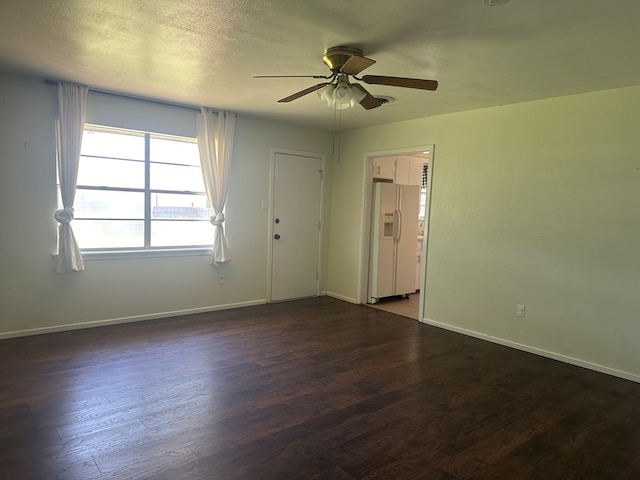 spare room featuring dark wood-type flooring, a textured ceiling, and baseboards