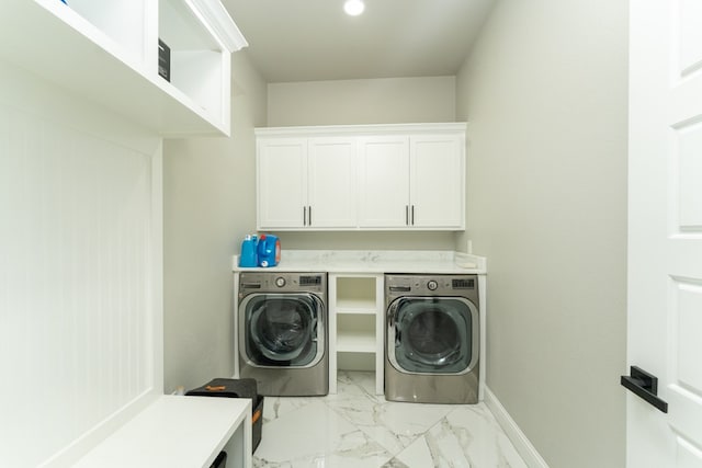 clothes washing area featuring washing machine and dryer and cabinets