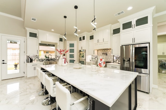 kitchen with appliances with stainless steel finishes, pendant lighting, white cabinetry, and a spacious island