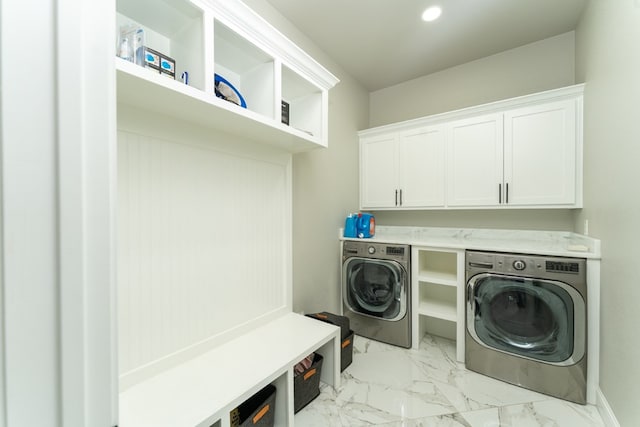 washroom with washer and dryer and cabinets