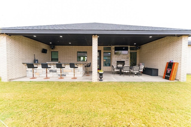 rear view of house with a patio, an outdoor bar, a yard, and a fireplace