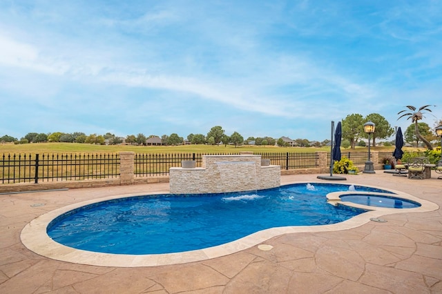 view of pool with a patio area, an in ground hot tub, pool water feature, and a rural view