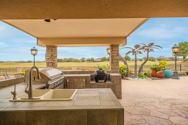 view of patio / terrace with a grill, a rural view, and exterior kitchen