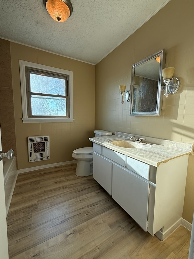 bathroom featuring a textured ceiling, heating unit, hardwood / wood-style floors, and vanity