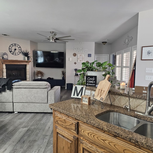 kitchen with wood-type flooring, sink, dark stone countertops, and ceiling fan