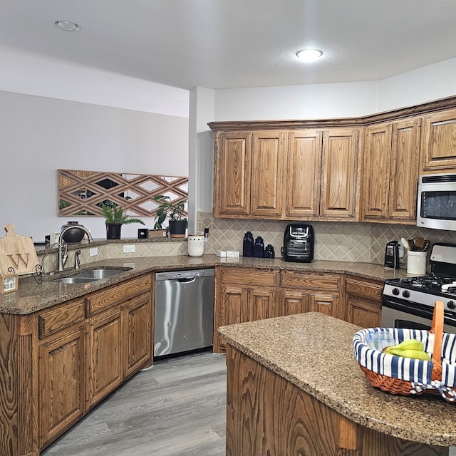 kitchen with backsplash, stainless steel appliances, sink, and stone counters