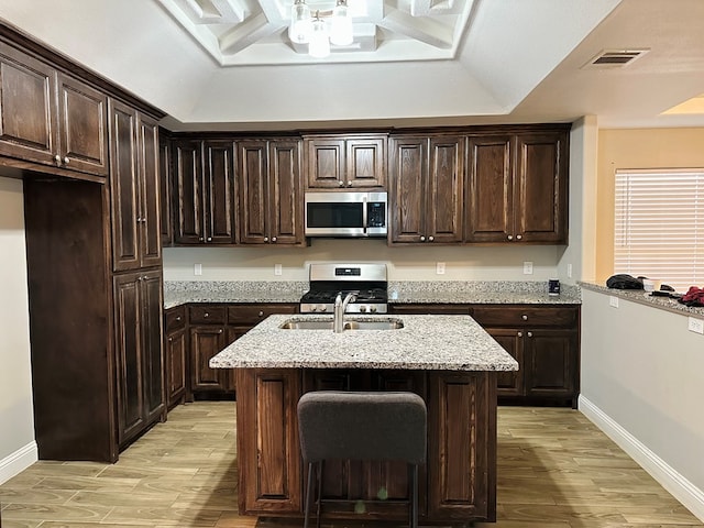 kitchen with dark brown cabinetry, a kitchen island with sink, and appliances with stainless steel finishes